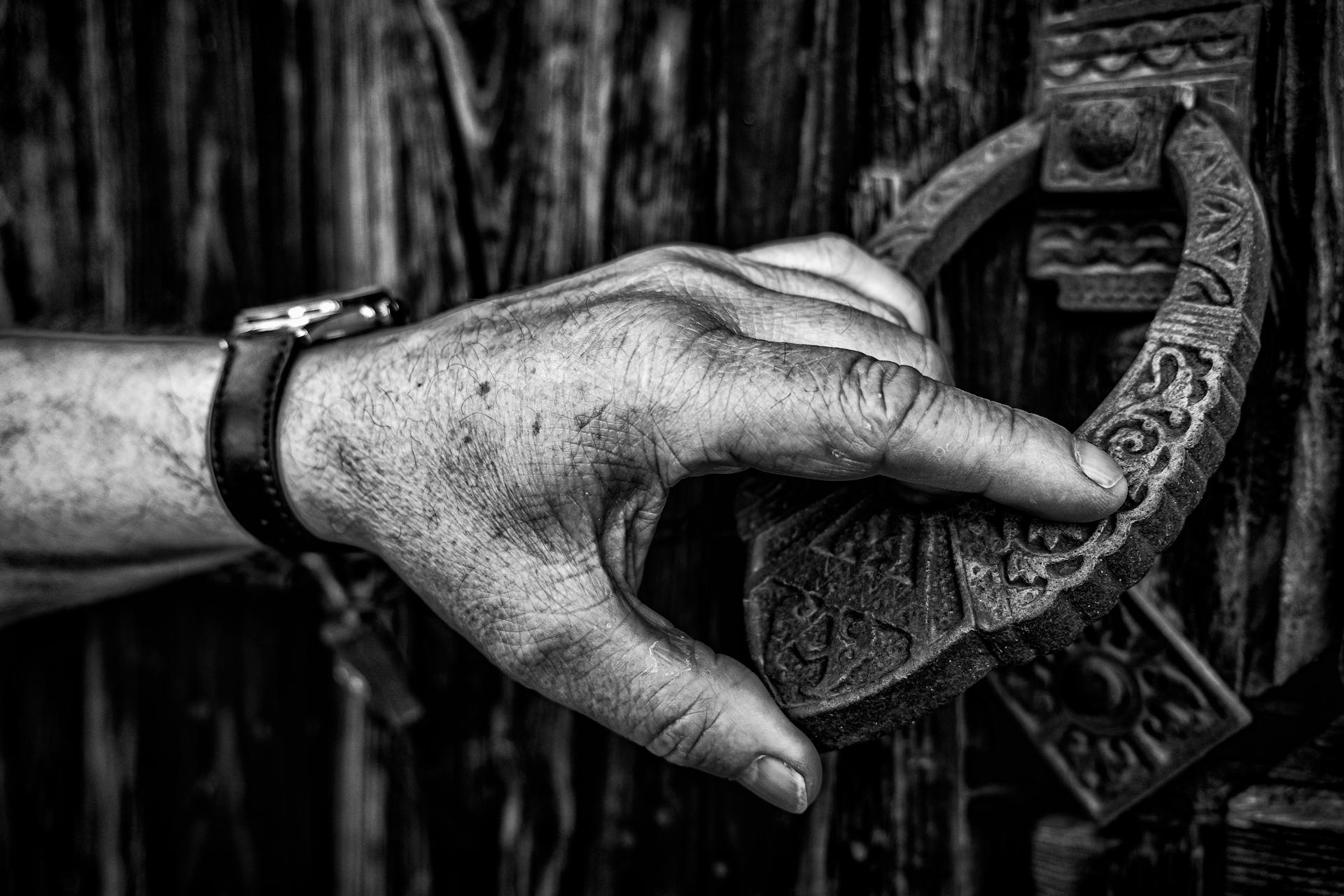 Close-up shot of a hand holding a door knocker | Source: Pexels