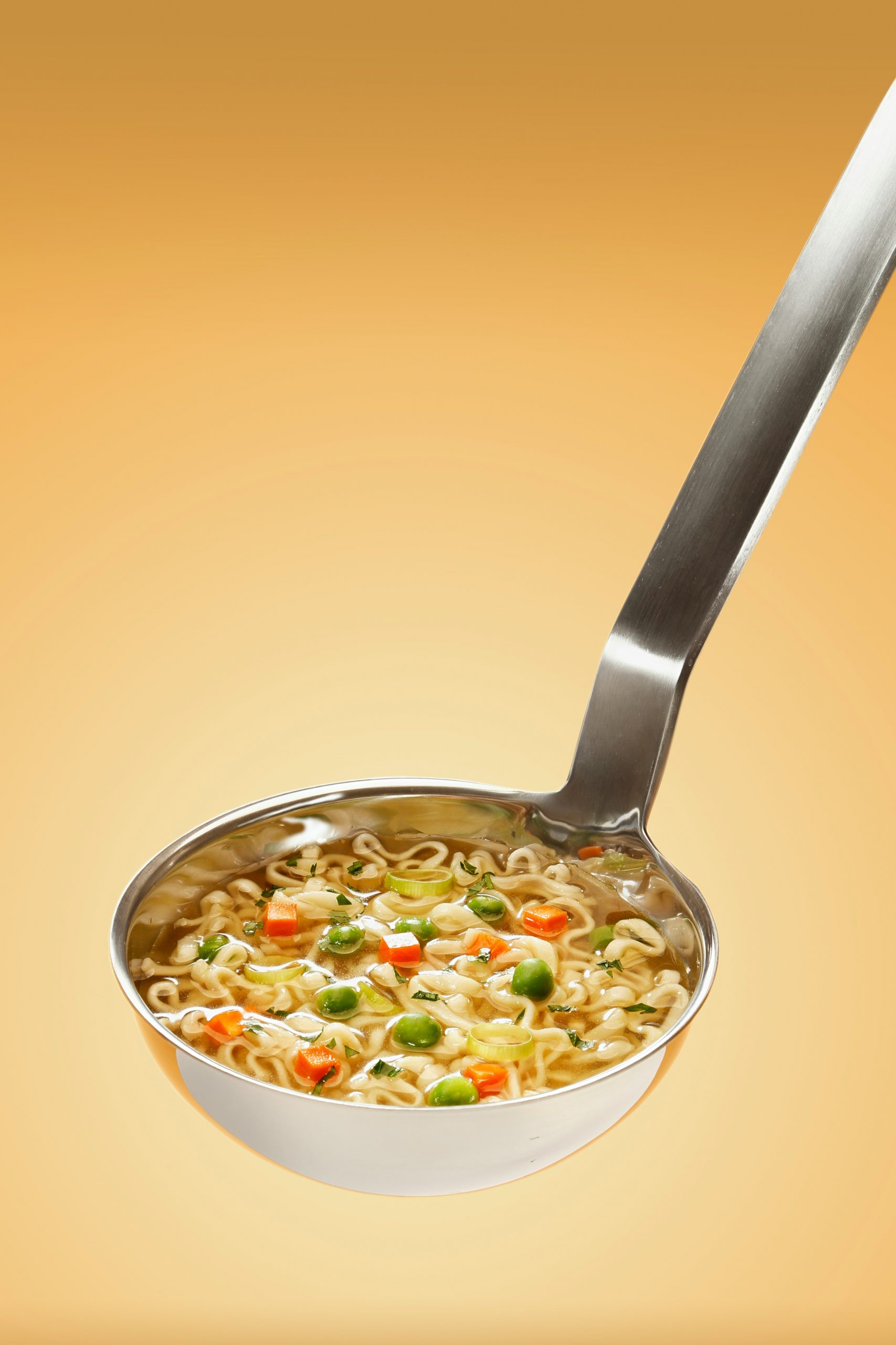 A steel ladle of chicken noodle soup | Source: Unsplash