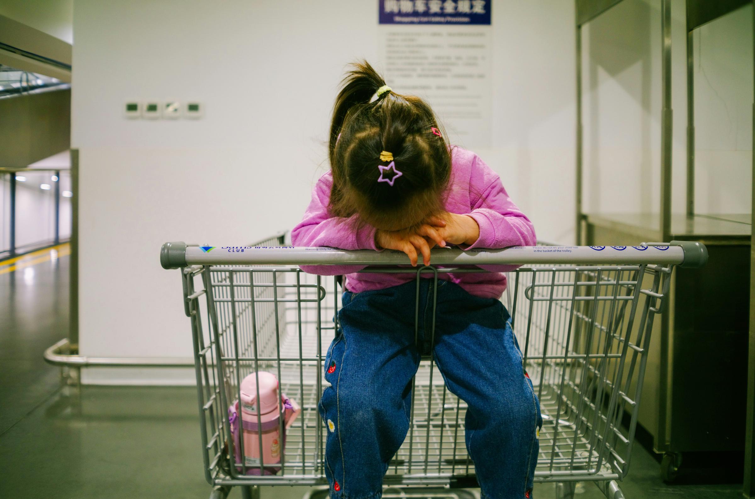 A little girl crying in a shopping cart | Source: Unsplash