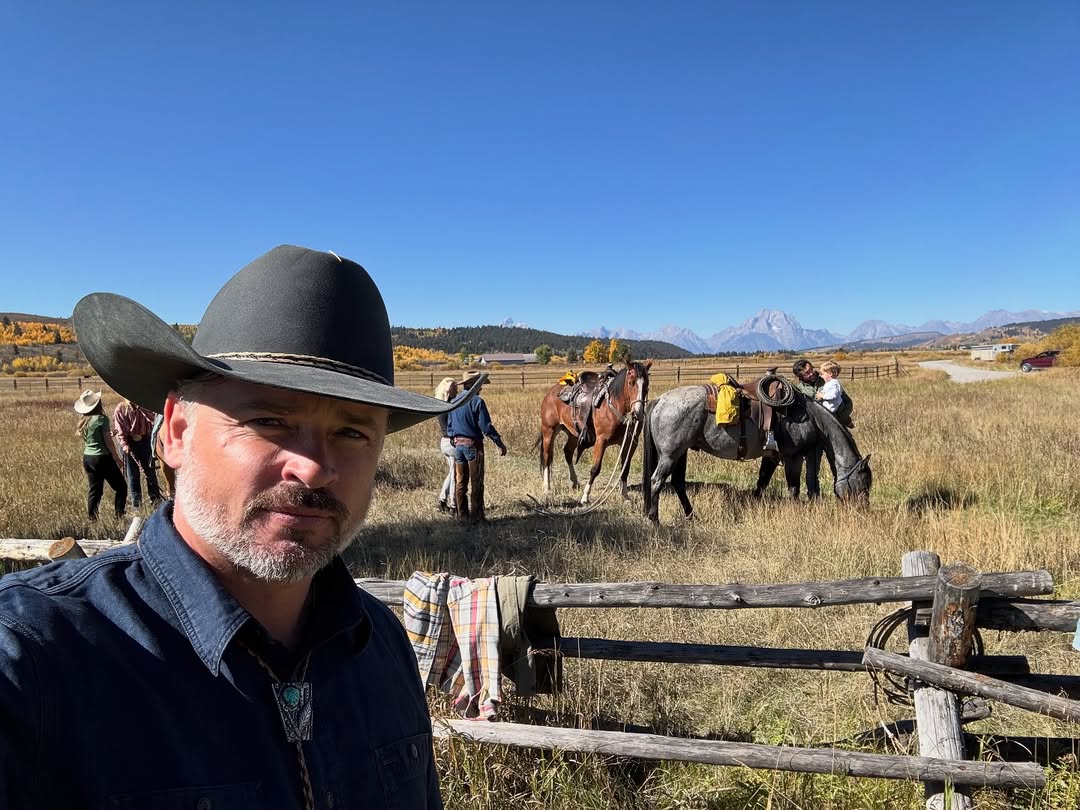 Tom Welling posing at a ranch with a background of people and horses in Wyoming on September 27, 2025 | Source: Instagram/tomwelling