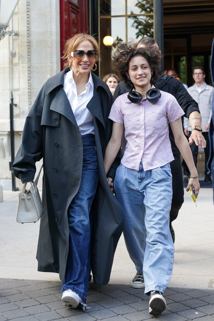 Jennifer Lopez and Emme Muñiz are spotted leaving their hotel in Paris, France. Both wear jeans and shirts, with Jennifer adding a long coat to her look while Emme has headphones resting around her neck. The duo share warm smiles as they head out together.