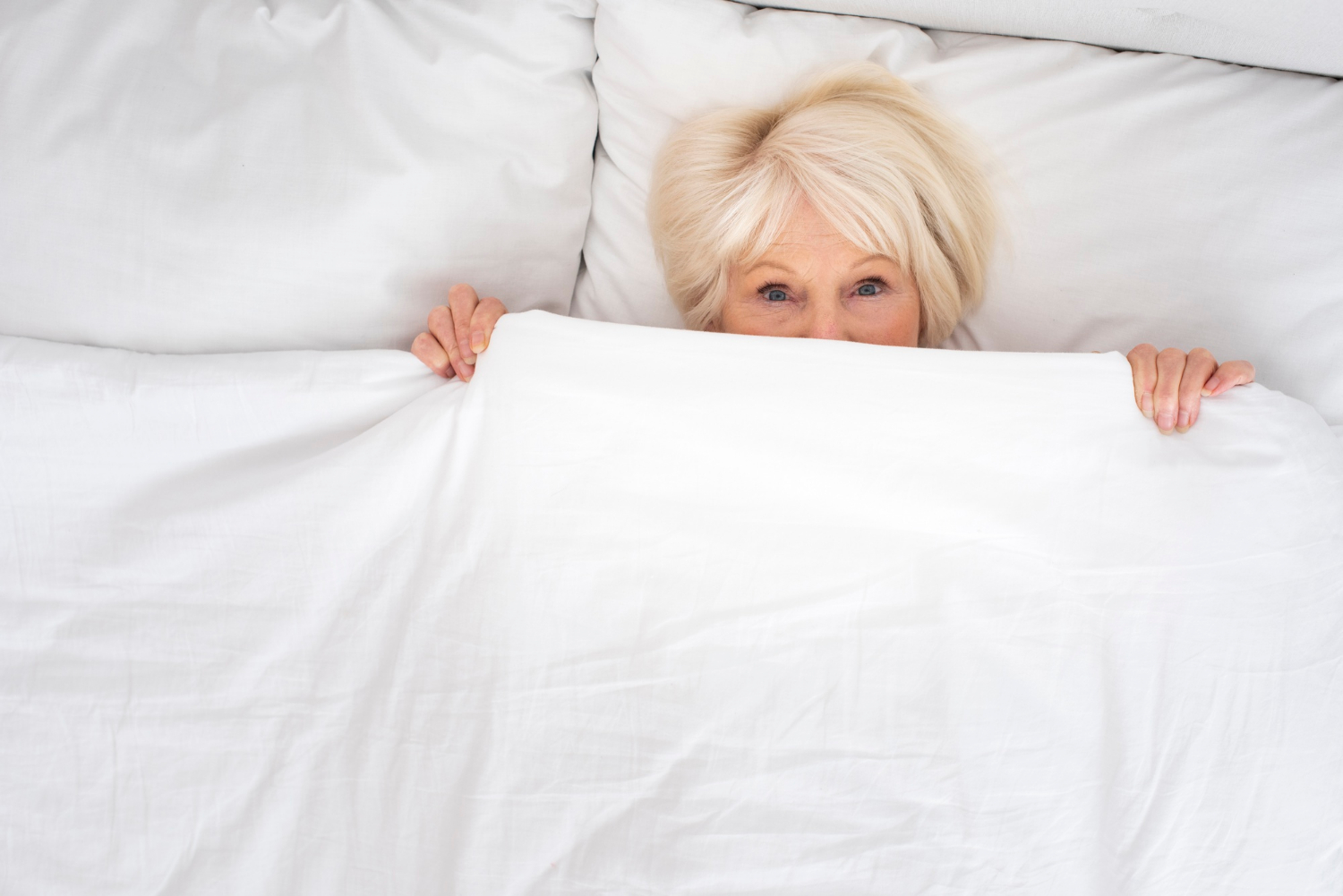 A startled senior woman lying in her bed | Source: Freepik