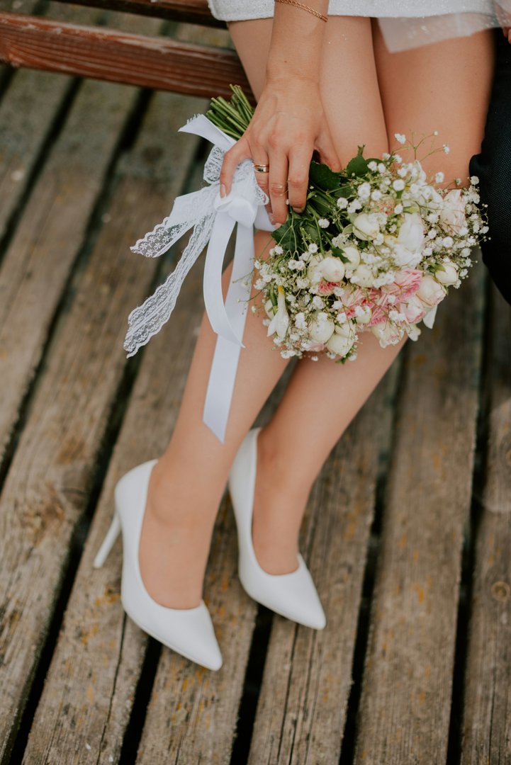 A bride in white heels holding flowers | Source: Unsplash