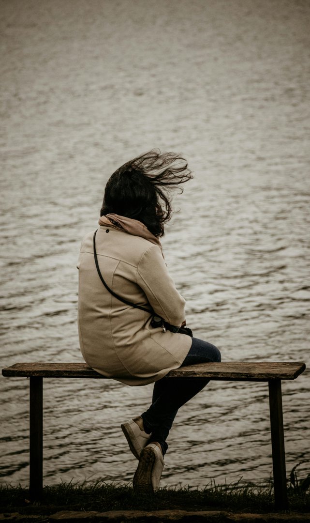 Woman sitting on a bench by the lake | Source: Pexels