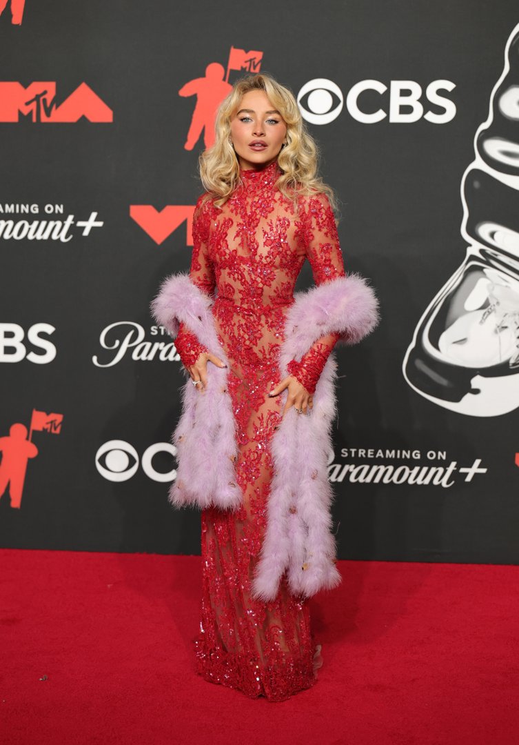 Sabrina Carpenter dazzled at the MTV Video Music Awards on September 7, 2025, in a sequined red sheer gown paired with a lavender feathered stole — a bold blend of vintage glamour and modern allure.