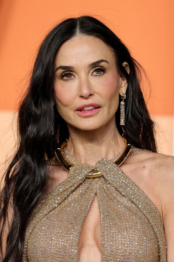 Demi Moore attends the 2025 Vanity Fair Oscar Party hosted by Radhika Jones at the Wallis Annenberg Center for the Performing Arts on March 2, 2025, in Beverly Hills, California. The actress styled her long, dark waves with a center part, pairing the look with a sparkling gold halter gown and statement earrings.