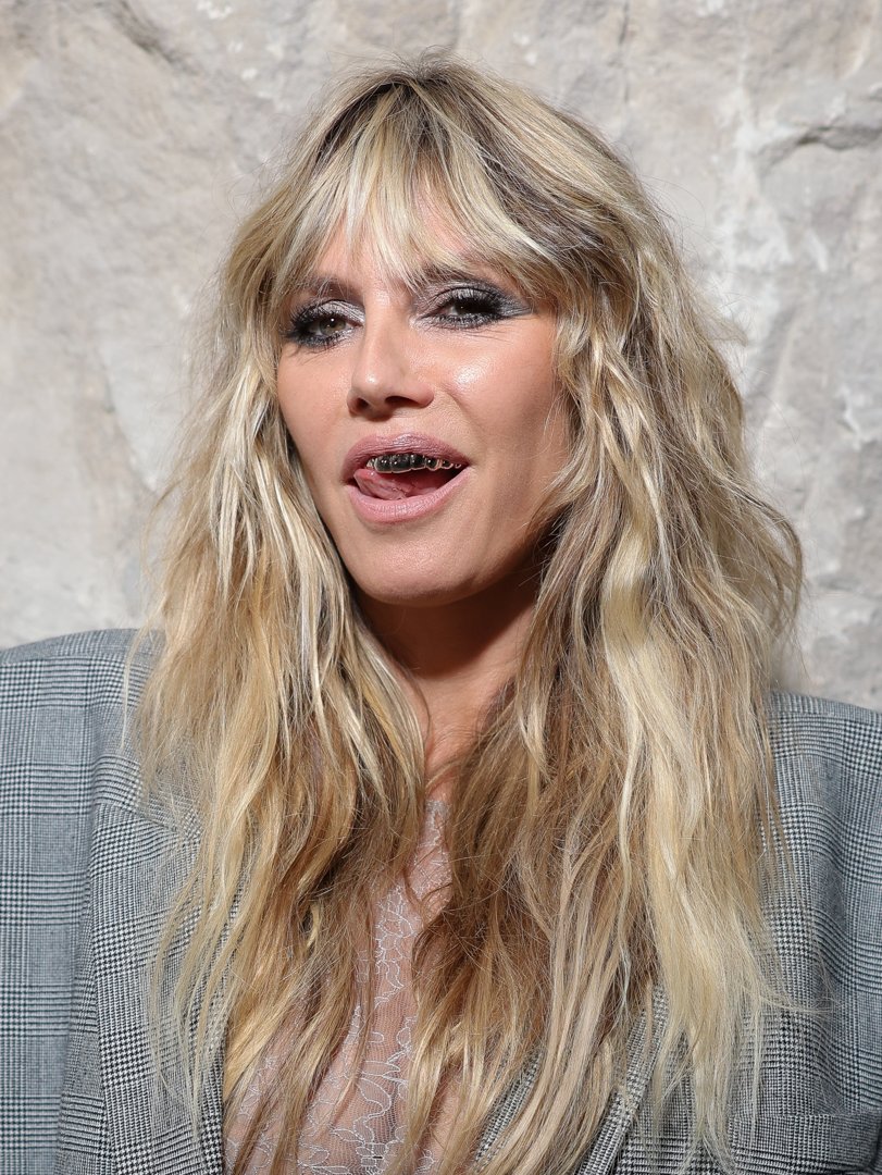 Heidi Klum completed her bold look with striking silver smoky eye makeup and edgy silver grills, adding a fun and daring edge to her ensemble.