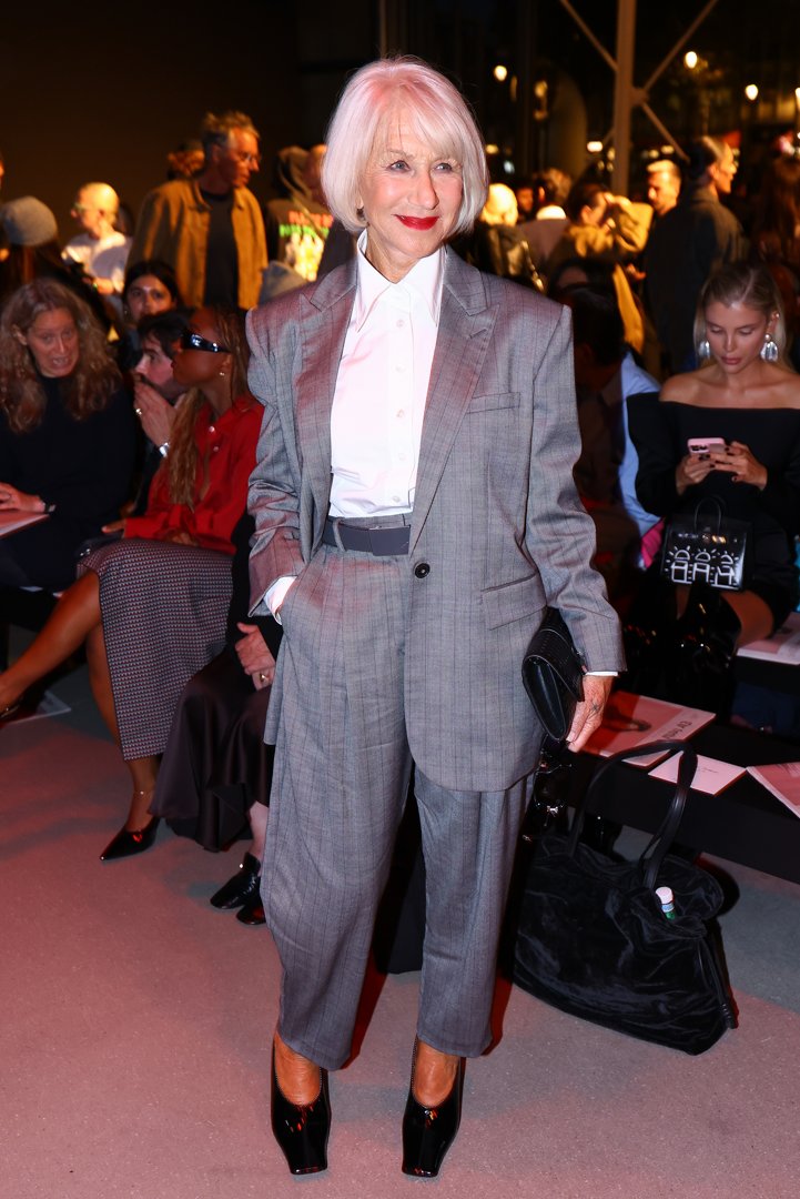 Dame Helen Mirren attended the Stella McCartney Women’s Spring/Summer 2026 show at Paris Fashion Week in France, wearing a sleek grey tailored suit. She paired a subtly pinstriped blazer with a white button-up shirt tucked into high-waisted trousers. She accessorized with a textured black clutch, patent black square-toe heels, and a grey belt, letting the suit remain the focal point.