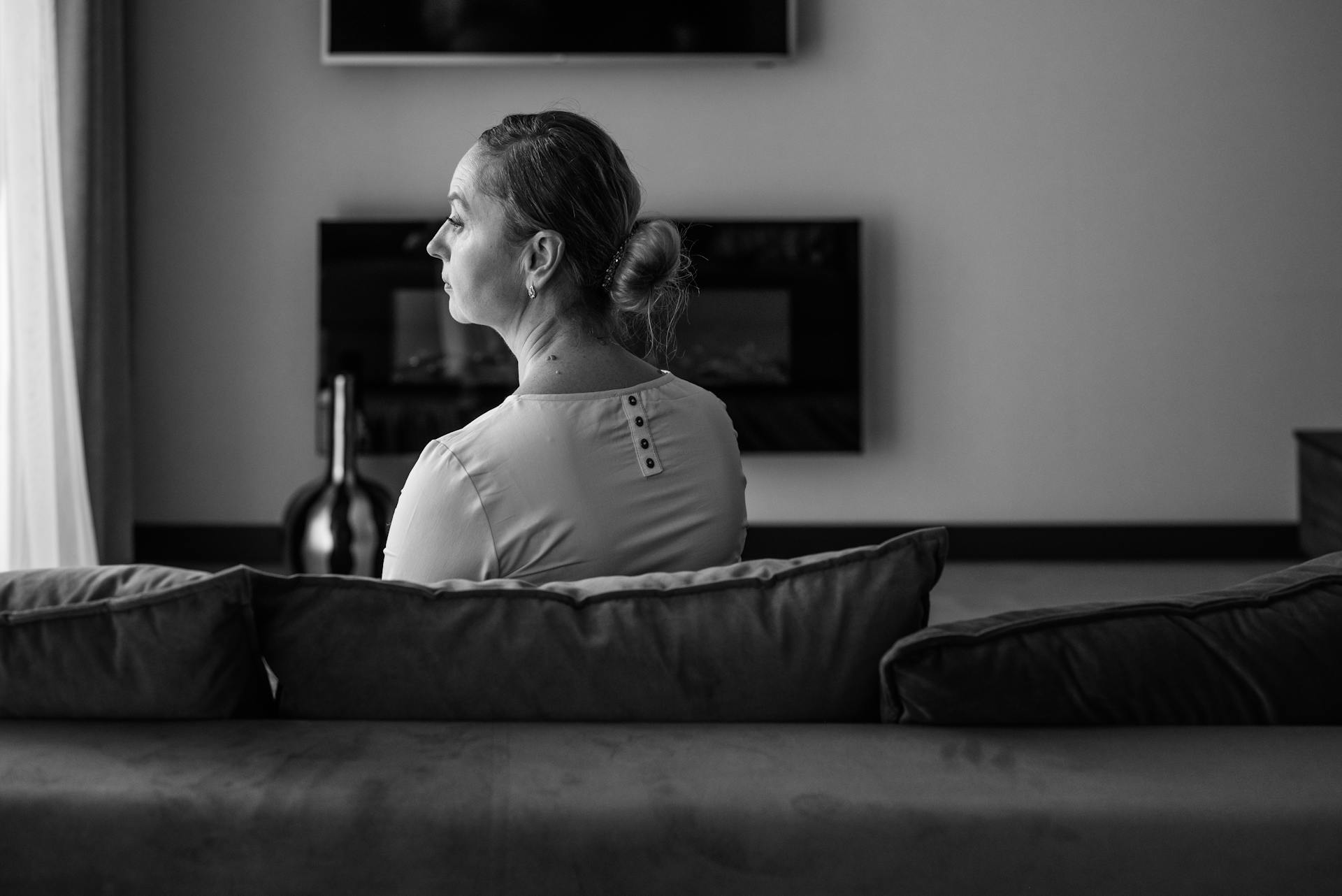 Grayscale photo of a woman sitting on the couch alone | Source: Pexels