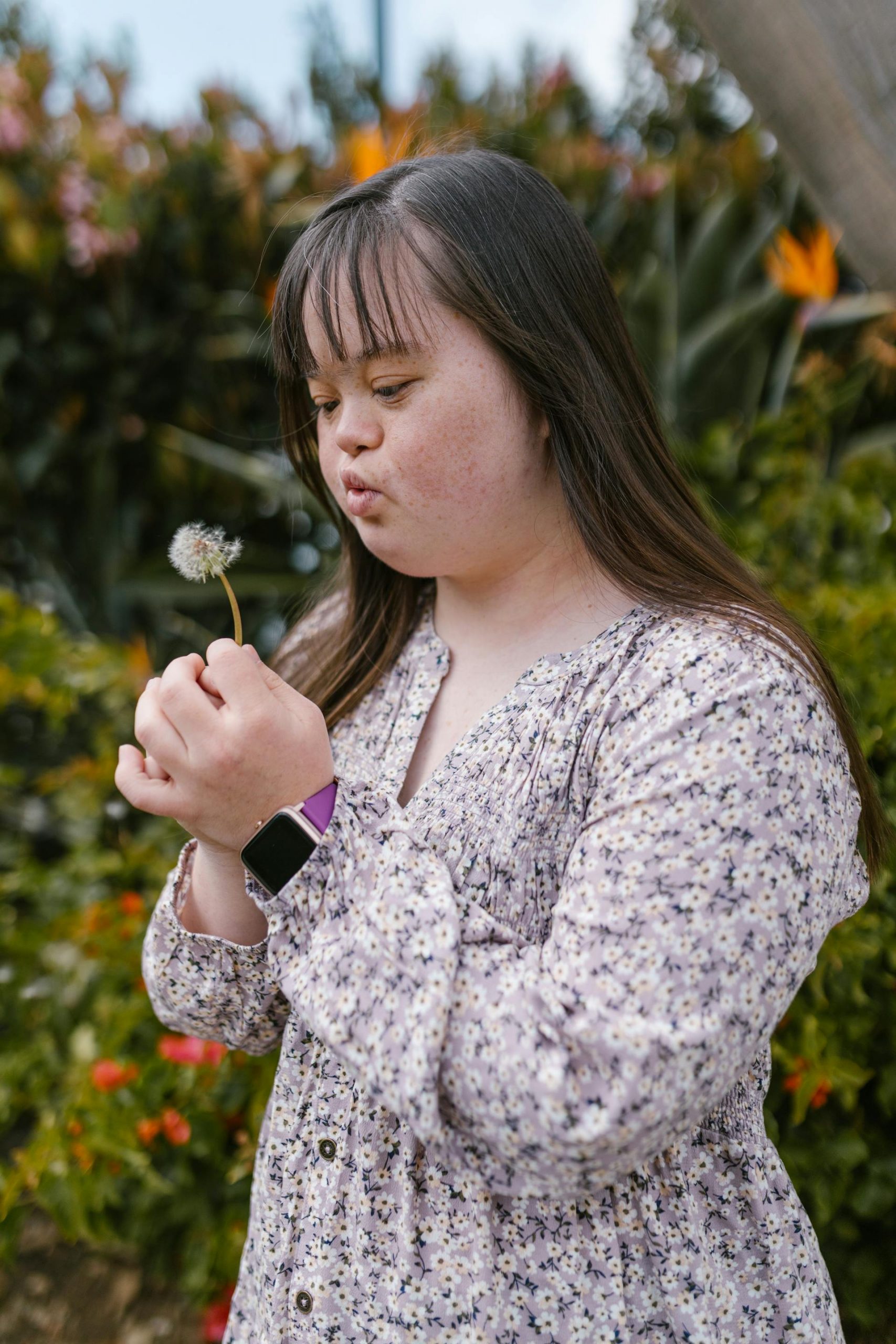 A Down syndrome girl holding a white dandelion | Source: Pexels