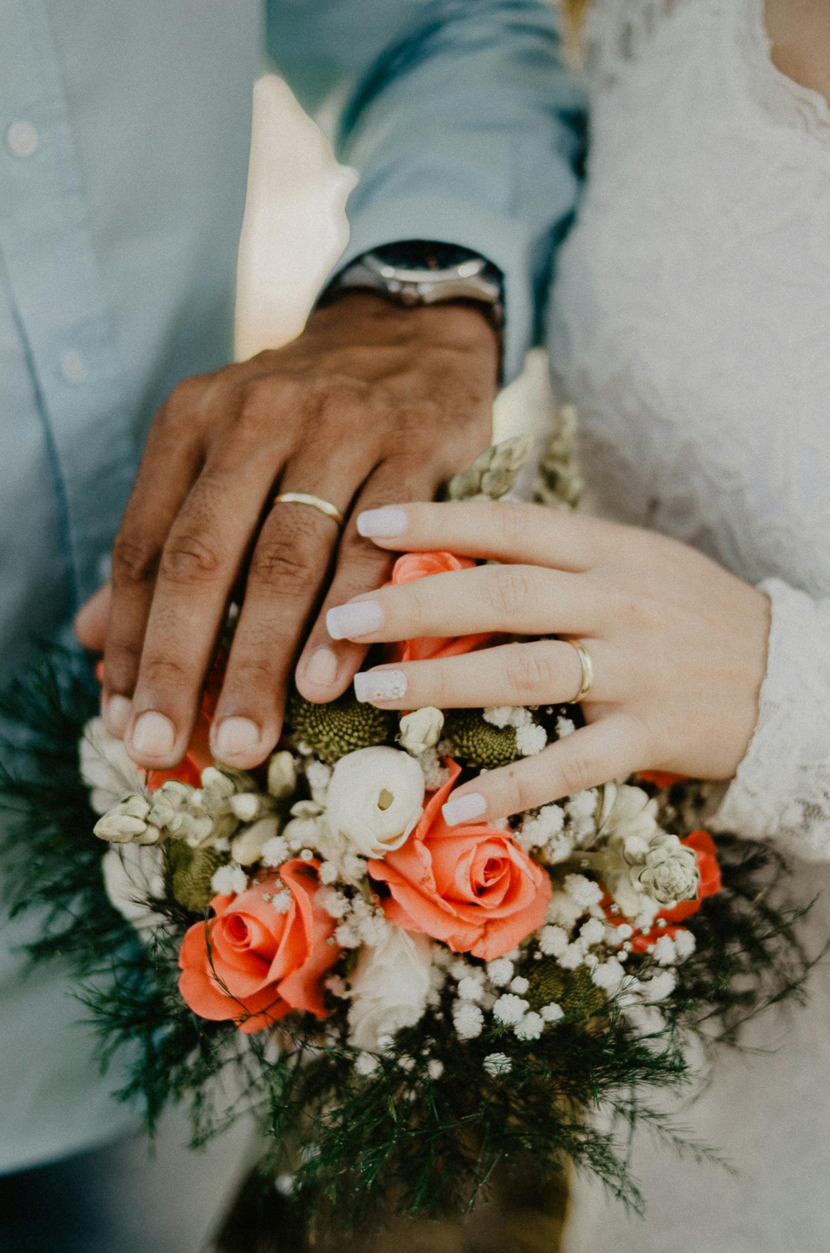 Close-up shot of a bride and groom's hands on top of a bouquet | Source: Pexels
