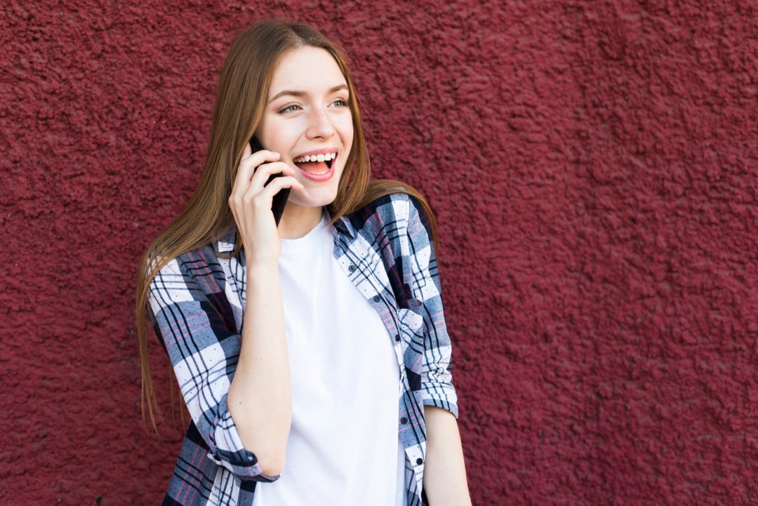 A cheerful woman talking on the phone | Source: Freepik