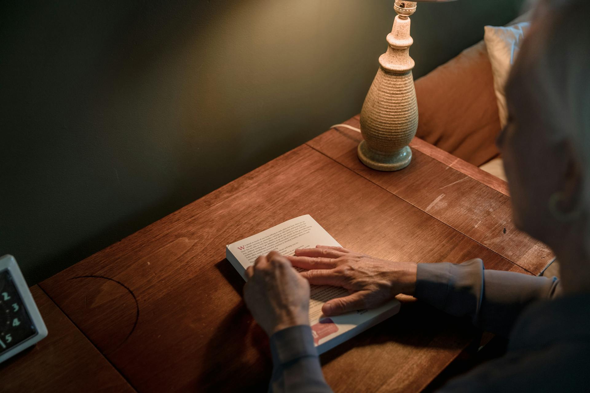 A senior woman holding a book on top of a desk | Source: Pexels