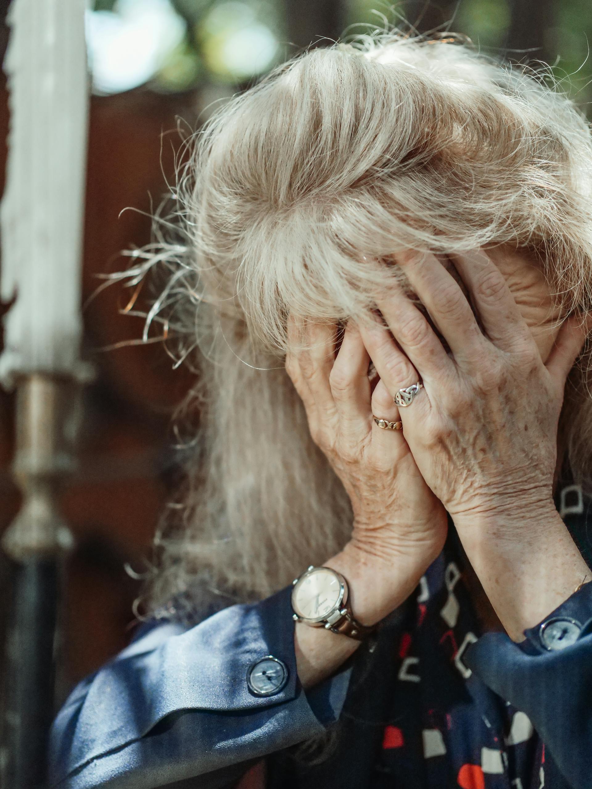 A senior woman covering her face with her hands | Source: Pexels