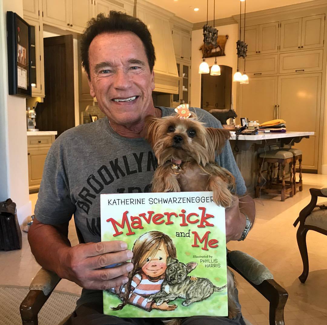 Arnold Schwarzenegger holds his dog and daughter Katherine’s book