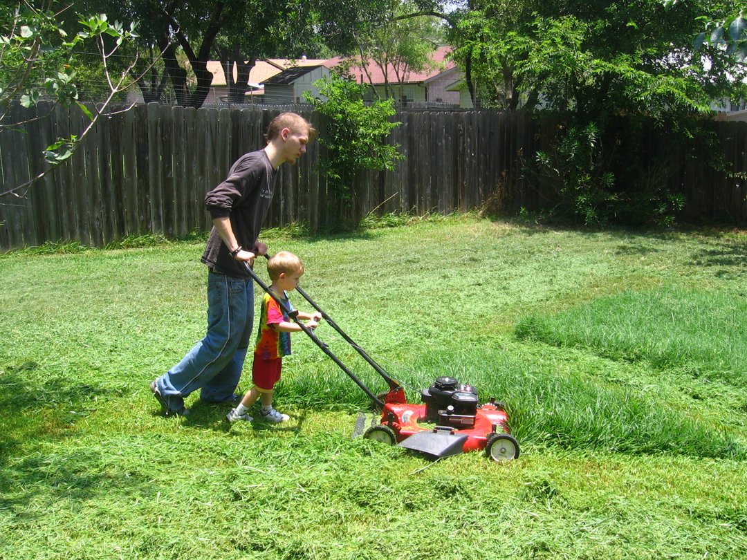 A man and his son mowing the lawn | Source: Flickr