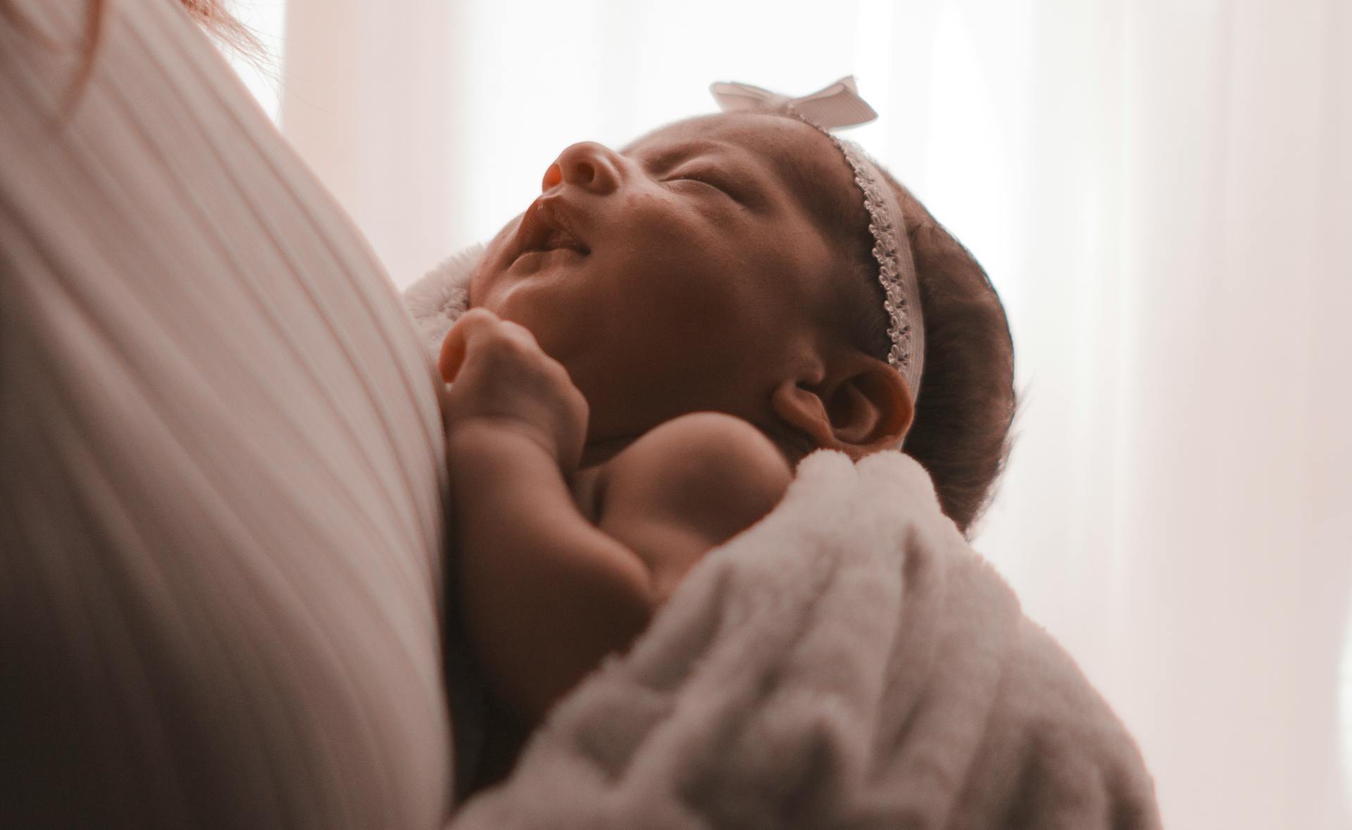 A woman carrying a baby girl | Source: Pexels