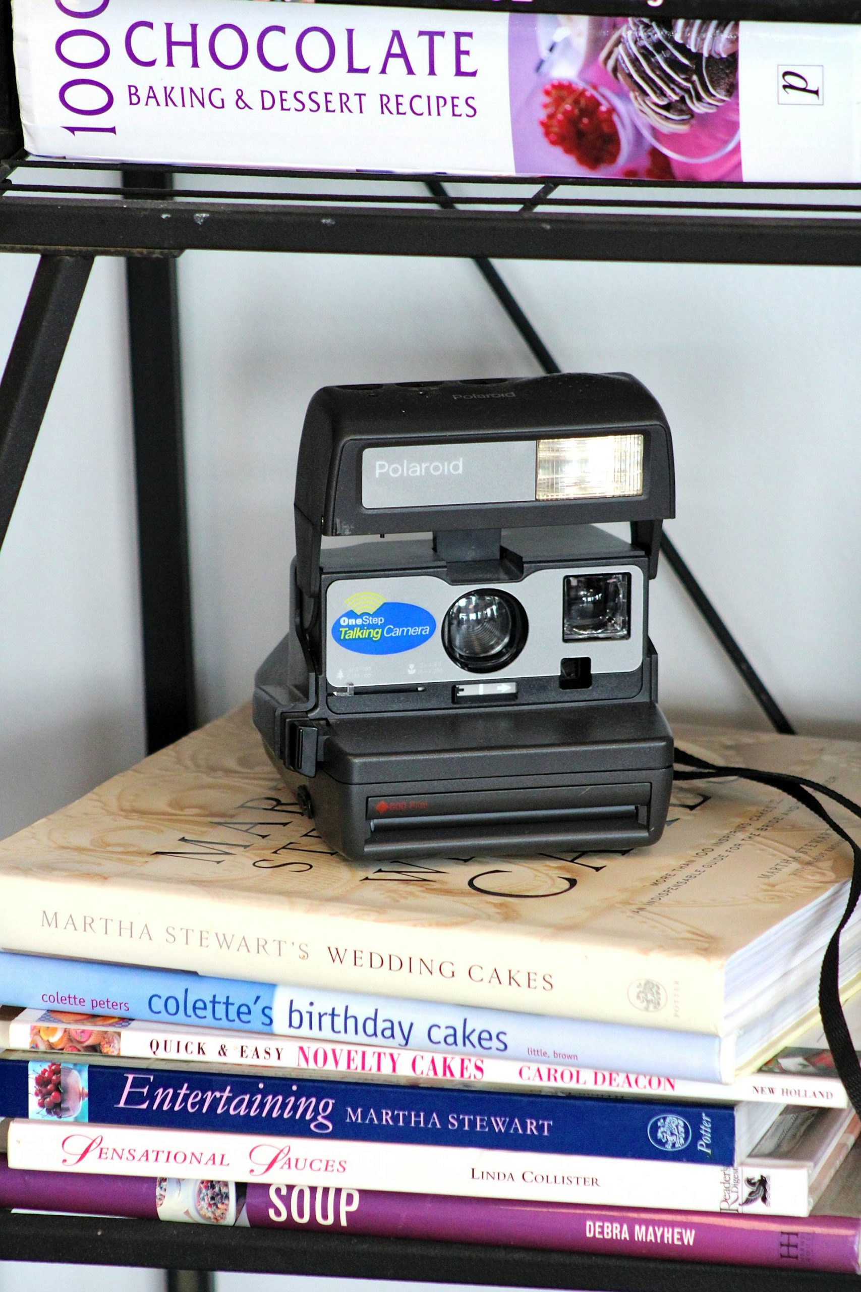 A vintage polaroid camera lying on top of cookbooks | Source: Pexels