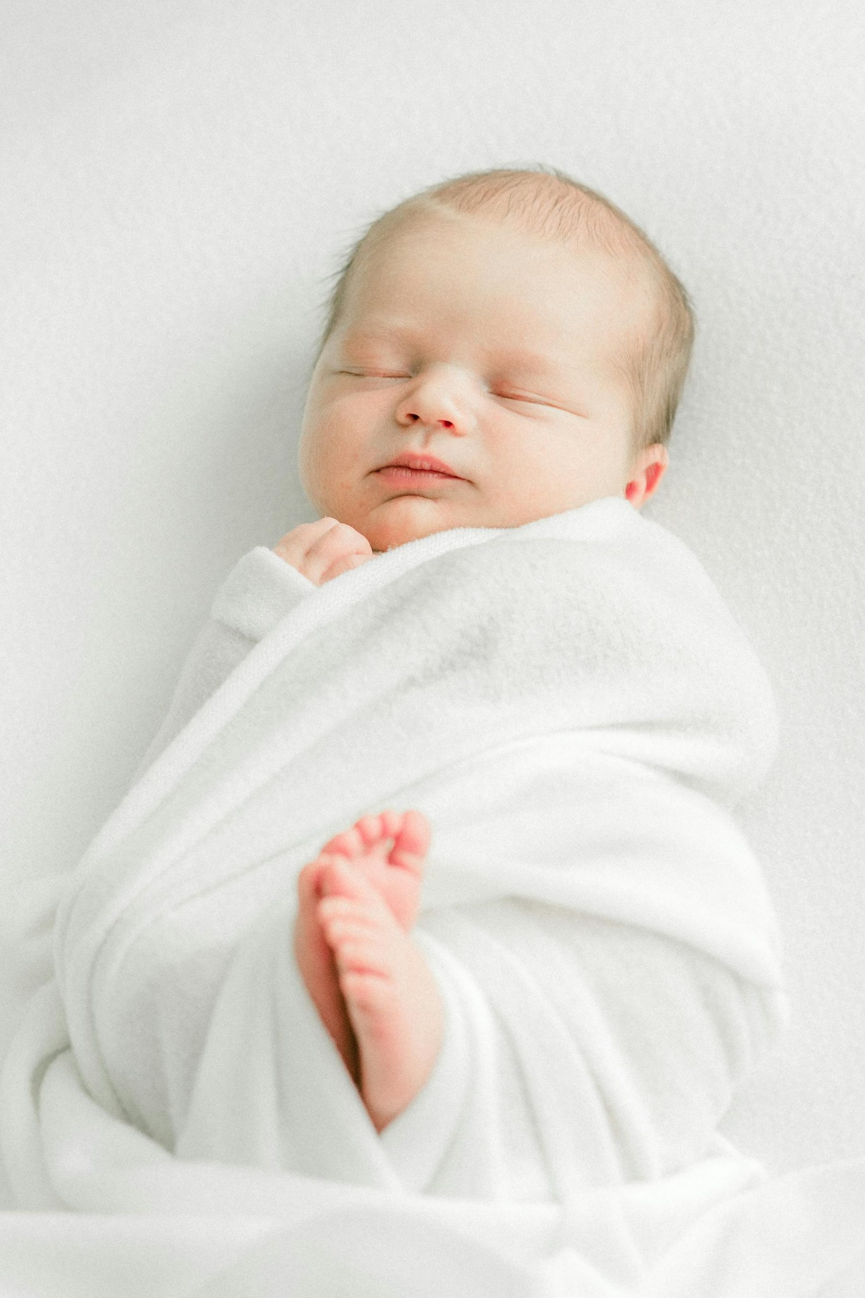 A sleeping newborn baby wrapped in a white blanket | Source: Pexels