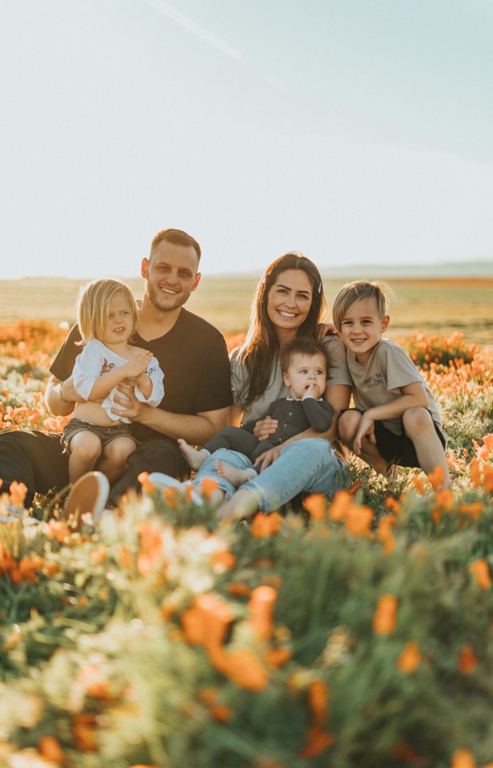 A happy couple with their three kids sitting together in a grassy field | Source: Unsplash