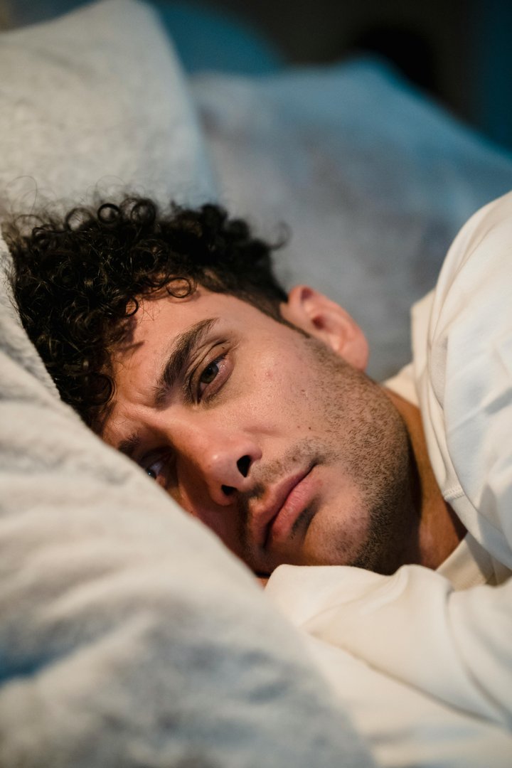 A frowning man lying in bed | Source: Midjourney