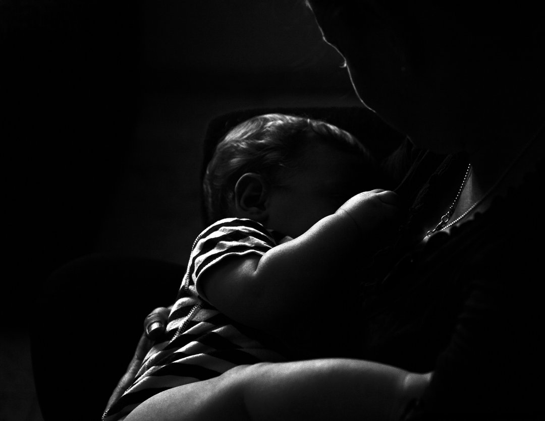 A person holding a baby in the dark | Source: Unsplash