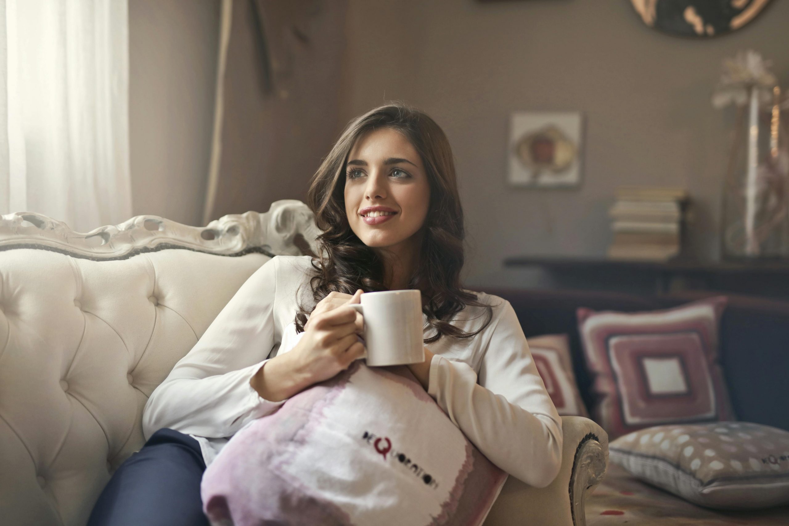 A woman sitting on a couch with a cup of tea | Source: Pexels