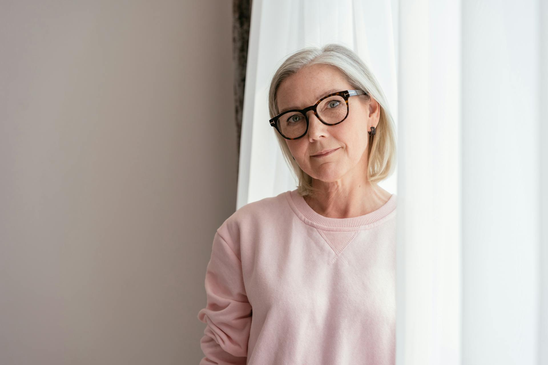 A middle-aged woman in a pink sweater wearing eyeglasses | Source: Pexels