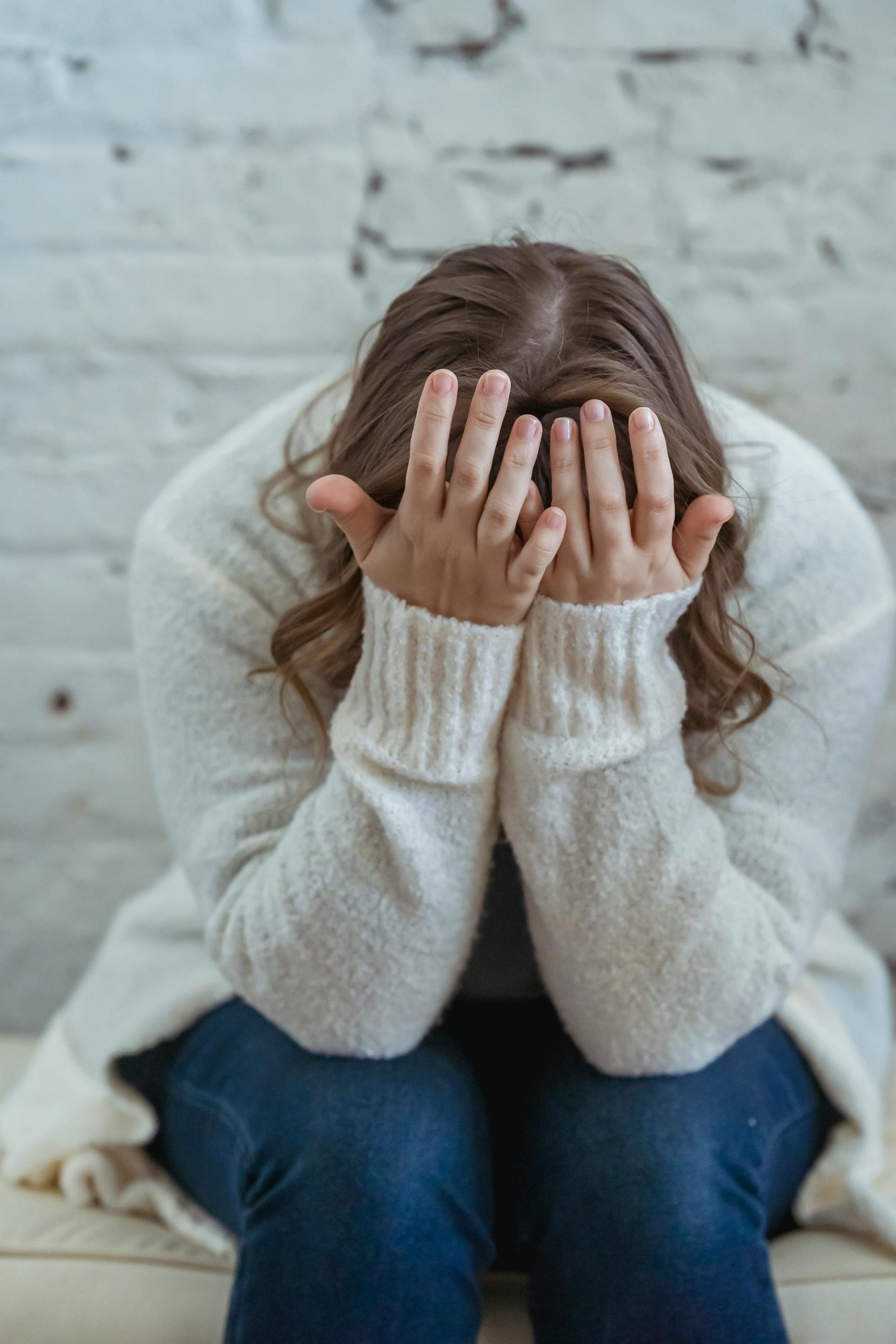 A distressed woman covering her face with her hands | Source: Pexels