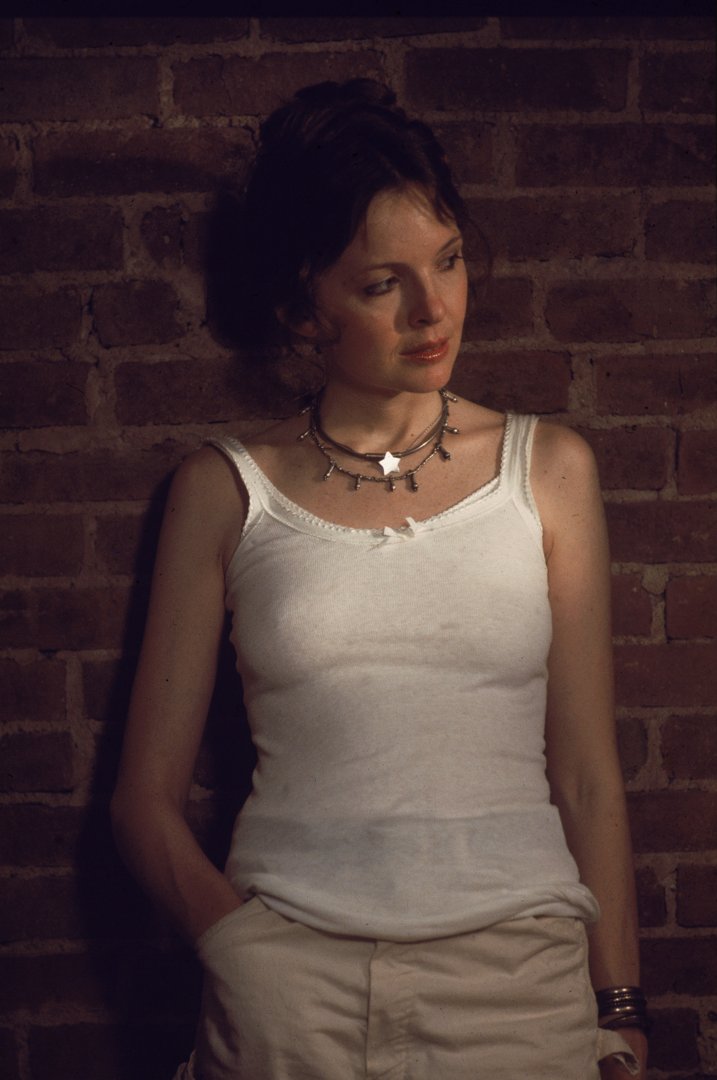Diane Keaton wears a white tank top and leans against a brick wall in a scene from 