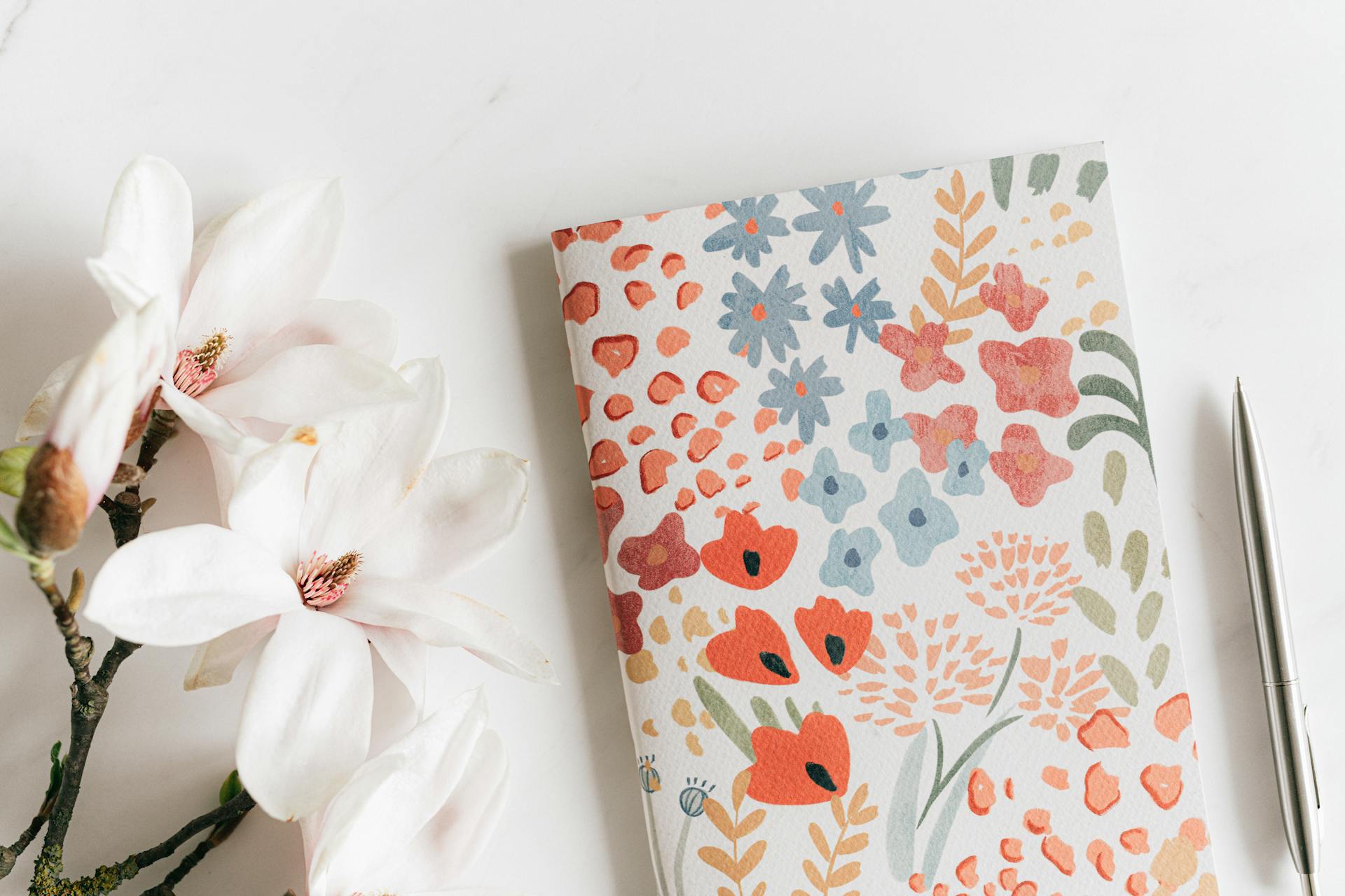 A diary and pen lying near white flowers | Source: Pexels