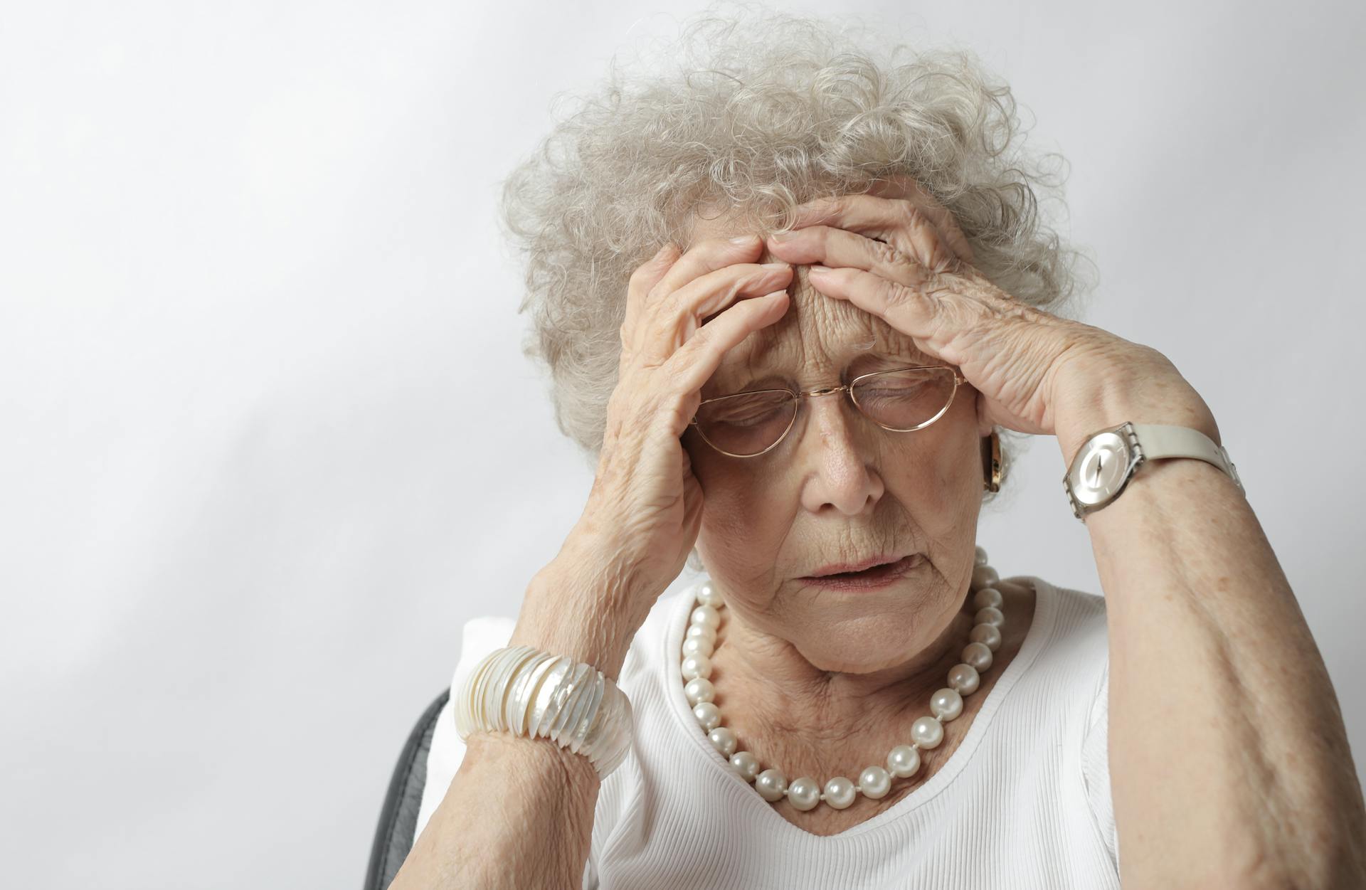 A distressed elderly lady holding her head | Source: Pexels