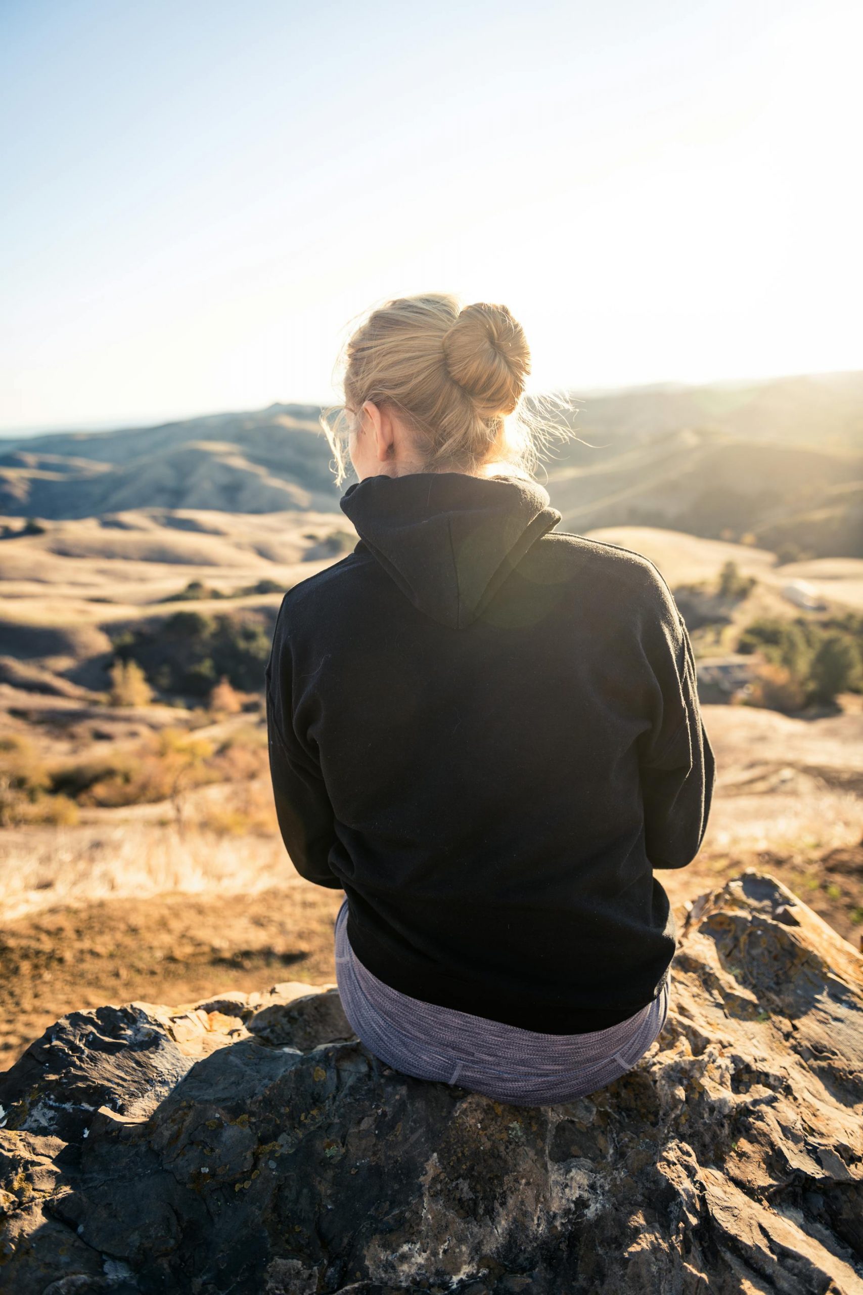 Woman in a black hoodie sitting on a rock | Source: Pexels