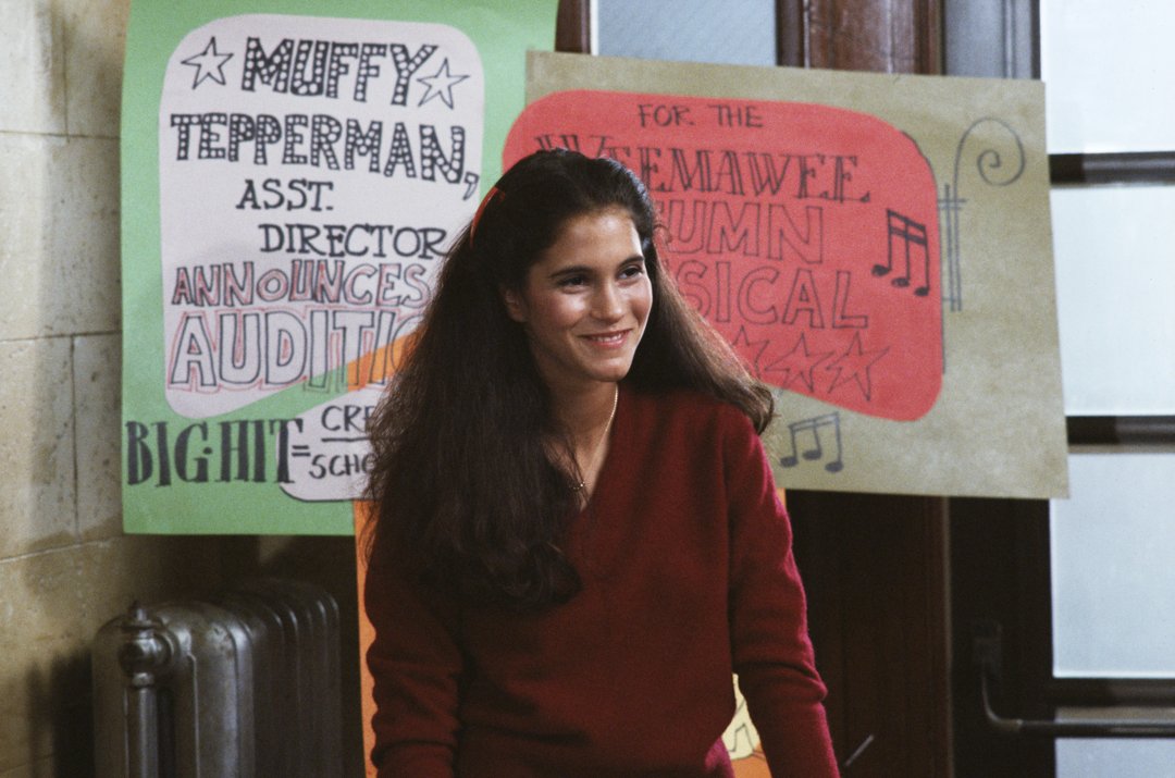 On a bustling TV set, Jami Gertz beamed in a deep red sweater, standing against a backdrop of playful audition posters.