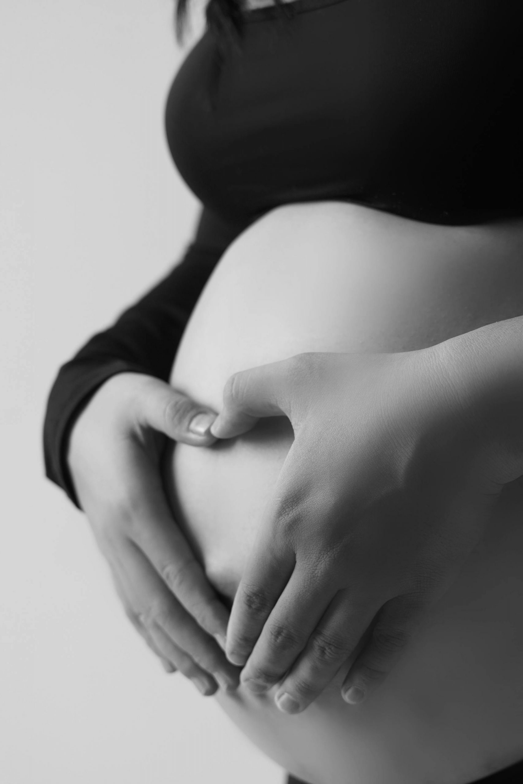 A grayscale photo of a pregnant belly with hands forming a heart | Source: Pexels