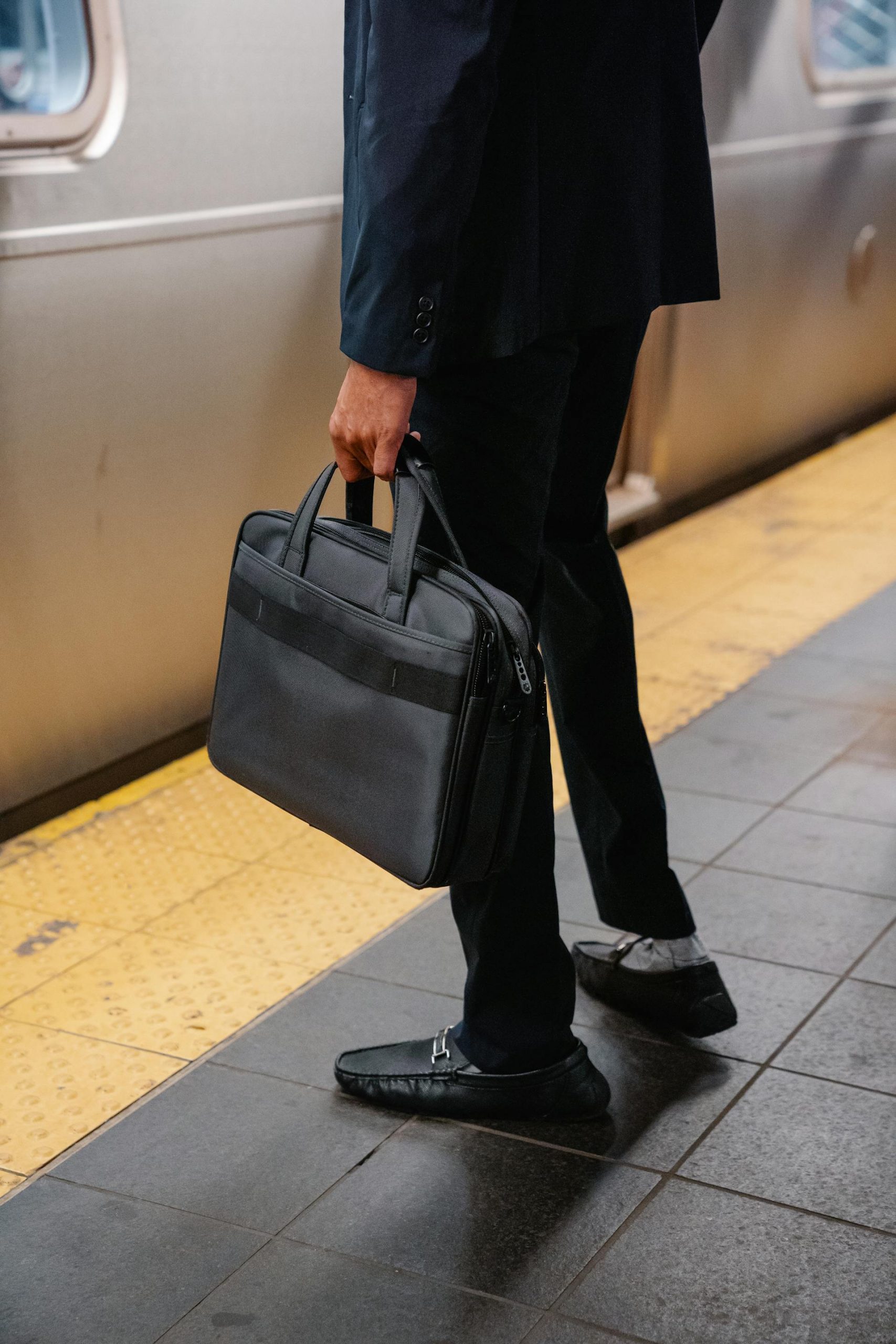 Close-up shot of a man carrying a bag while standing on a subway platform | Source: Pexels