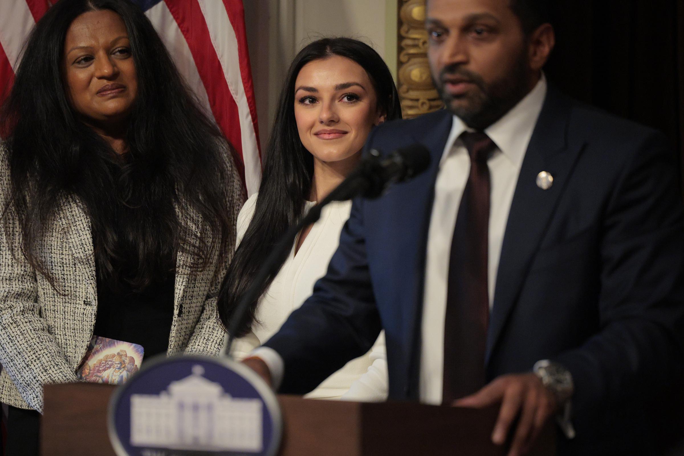 Kash Patel speaks as his girlfriend Alexis Wilkins (C) looks on during his swearing-in ceremony in the Indian Treaty Room in the Eisenhower Executive Office Building on February 21, 2025, in Washington, DC | Source: Getty Images