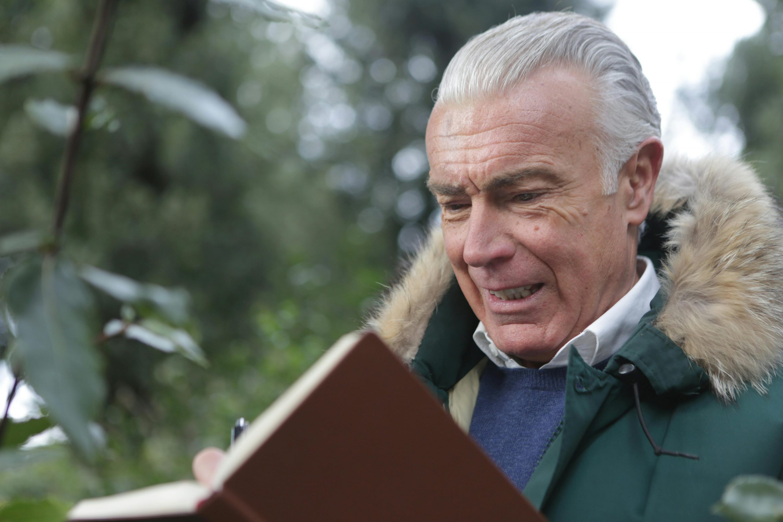 An older man with a book open in front of him | Source: Pexels