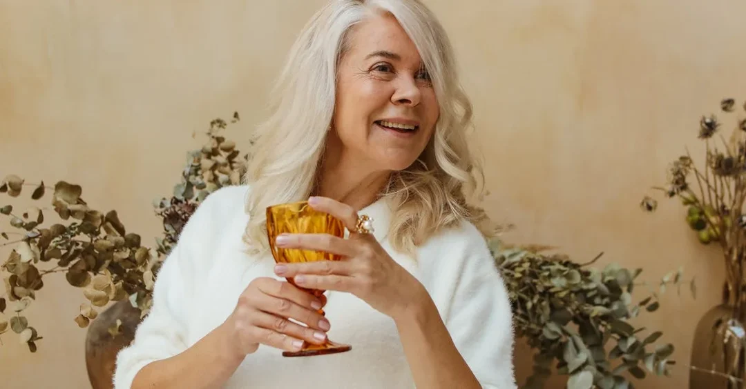 A senior woman holding a goblet and smiling | Source: Pexels