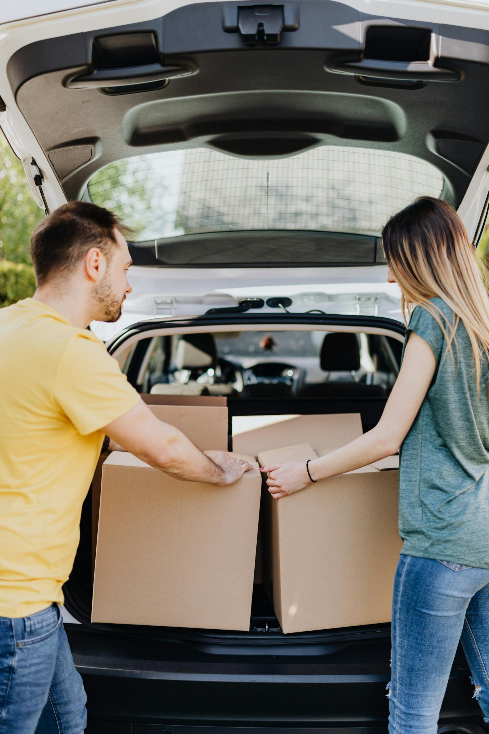 A couple taking out carton boxes from a car's trunk | Source: Pexels