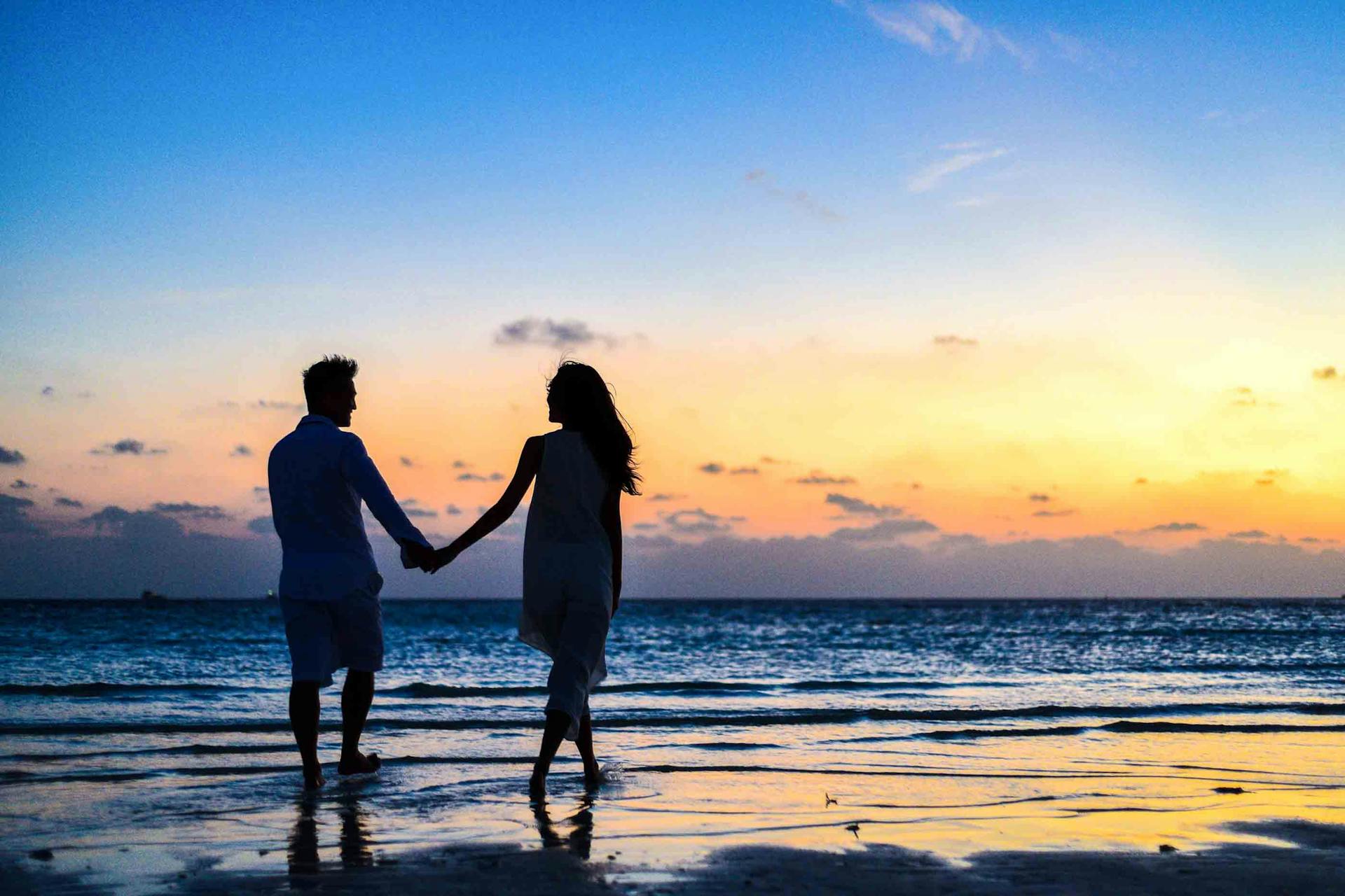 A couple holding hands while standing on the seashore | Source: Pexels