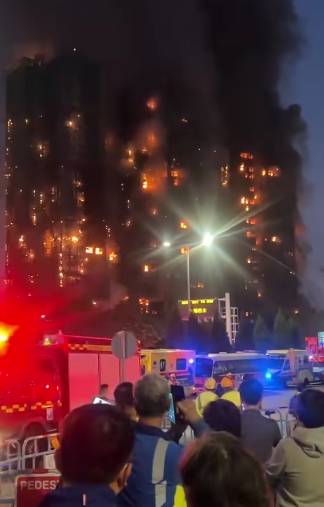 Flames rage through the upper floors of the Wang Fuk Court housing complex as emergency vehicles surround the area in a desperate response effort. The fire, which spread rapidly across multiple towers in Hong Kong's Tai Po district, was believed to be worsened by flammable renovation materials and bamboo scaffolding. | Source: TikTok/highlight_kutin