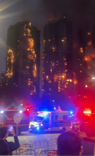 Thick black smoke billows into the dusk sky as people gather behind barricades, staring helplessly at the unfolding catastrophe. Firefighters struggled to access upper floors due to extreme heat and structural collapse, while frantic families tried to reach loved ones trapped inside the 31-storey buildings. | Source: TikTok/highlight_kutin
