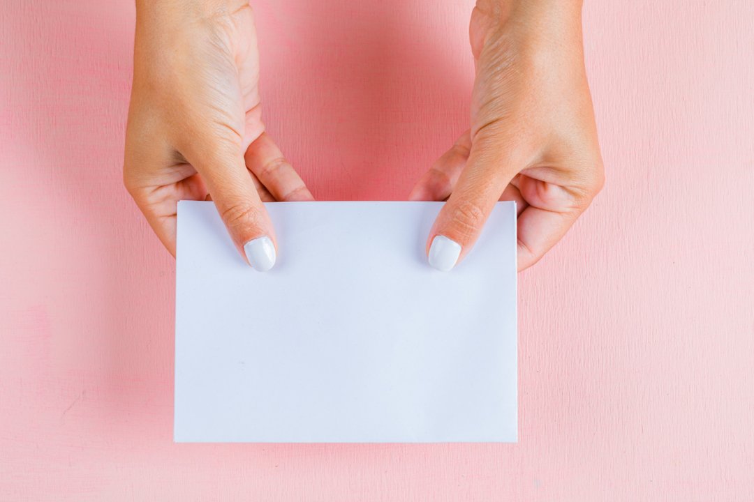 A woman holding a sheet of paper | Source: Freepik