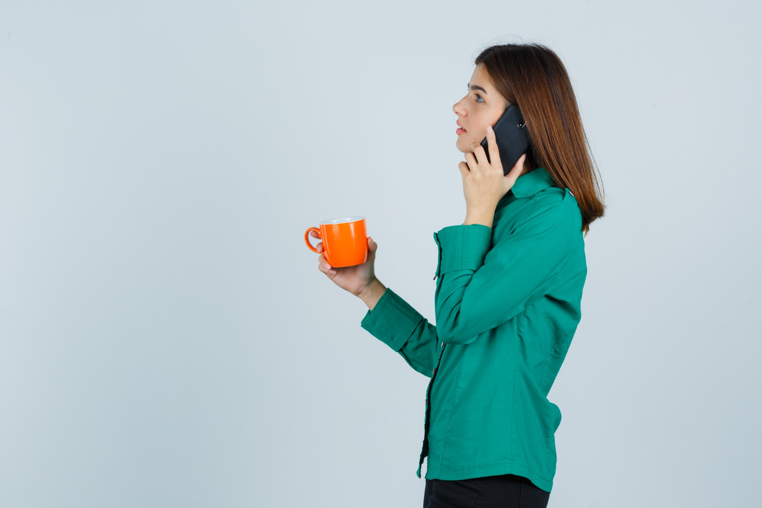 A woman holding an orange cup and talking on the phone | Source: Freepik
