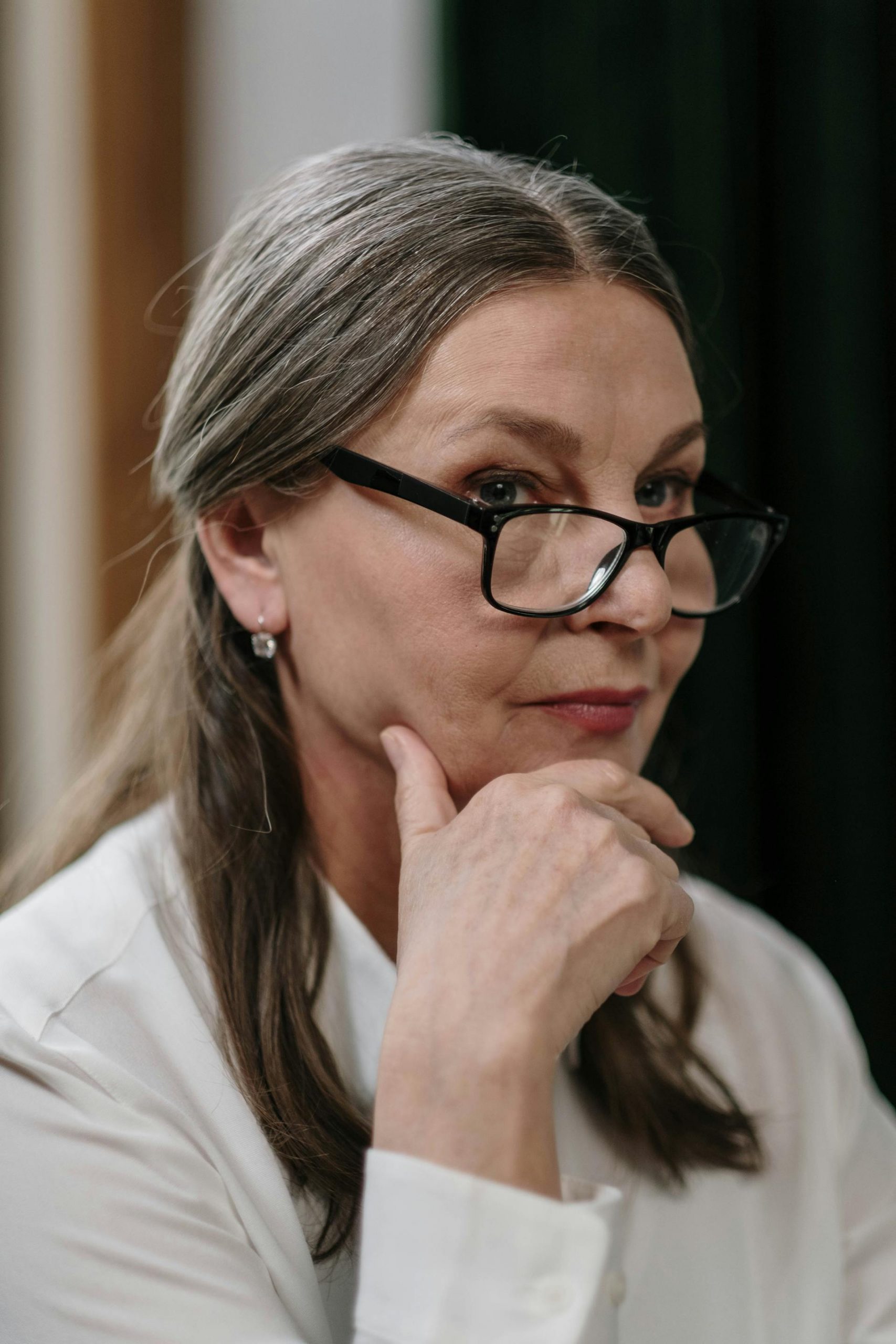 An elderly woman with a hand on her chin | Source: Pexels
