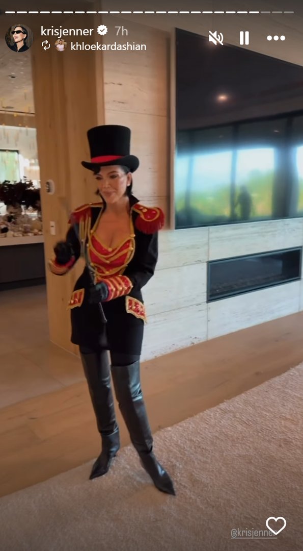 In a November 1 post, Jenner stepped into the ring as a glam ringmaster. Her costume featured a fitted black coat with bold red accents, gold buttons, and epaulets with fringe. A plunging red-and-gold top added flair beneath the tailored jacket, while thigh-high black boots and leather gloves completed the look. She topped it all off with a classic black top hat and a whip in hand — commanding the room with circus-chic authority. | Source: Instagram/krisjenner