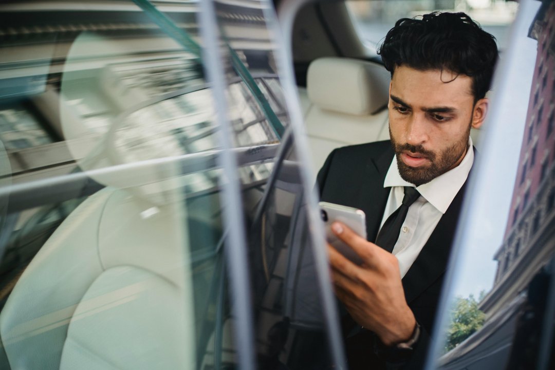 A serious man looking at his phone while sitting in a car | Source: Pexels