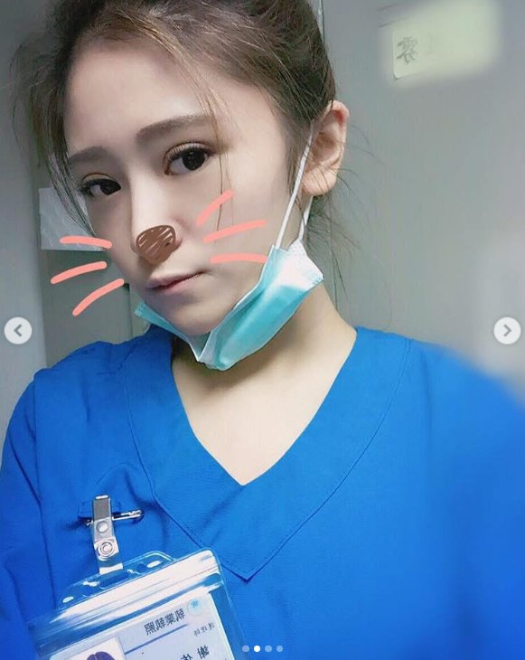 Iris Hsieh poses for a selfie in blue medical scrubs with a surgical mask pulled below her chin, as posted in July 2025 | Source: Instagram/irisirisss900