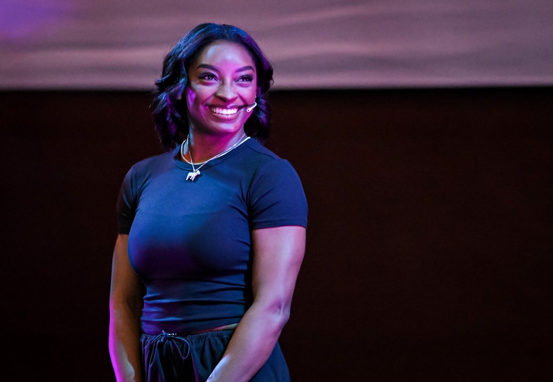 Biles lights up the stage with a radiant smile during the opening ceremony of her gymnastics clinic at Youth Olympic Park in Villa Soldati on October 9, 2025, in Buenos Aires, Argentina. The champion athlete welcomed young gymnasts from around the world to a day of inspiration, movement, and mentorship.